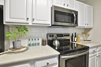 A kitchen with white cabinets and a black stove top oven